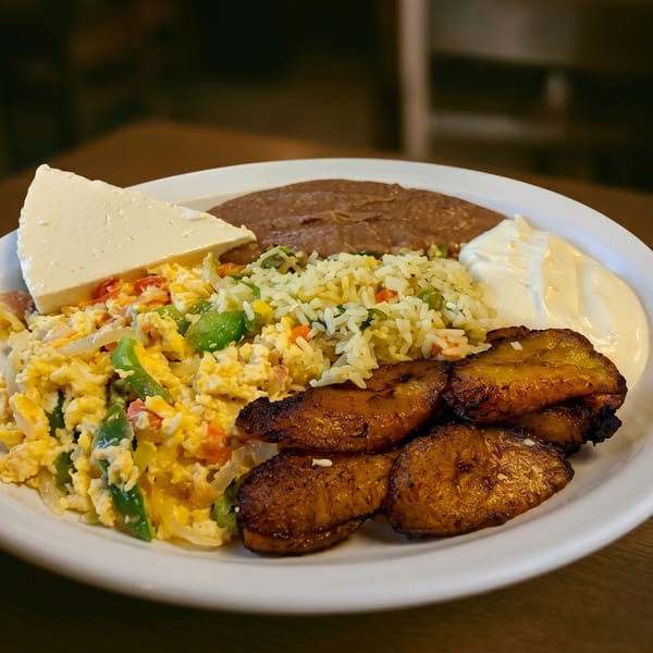 A white plate with scrambled eggs, rice, refried beans, fried plantains, cheese, and sour cream.